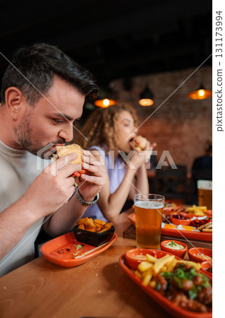 Couple enjoying burgers and beer at a restaurant Couple enjoying burgers and beer at a restaurant 131173994
