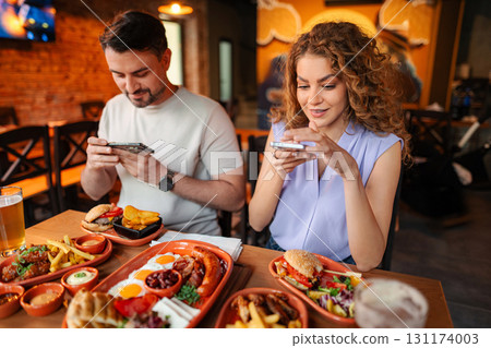 Young couple taking photos of food in restaurant 131174003