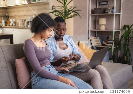 Mother and daughter shopping online using laptop and credit card at home 131174009