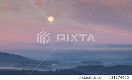 Full moon glows above a misty landscape, casting a soft, ethereal light over the scene. Full moon glows above a misty landscape, casting a soft, ethereal light over the scene. 131174450
