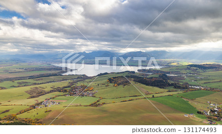 The Liptovska Mara dam in northern Slovakia, Europe. Scenic view of a large lake surrounded by green fields and distant mountains under a cloudy sky. 131174493