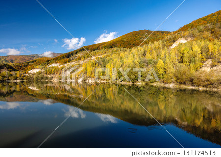 Autumn landscape with reflection of colorfull hills in the lake. Flooded quarry near the village Sutovo in Slovakia, Europe. Autumn landscape with reflection of colorfull hills in the lake. Flooded quarry near the village Sutovo in Slovakia, Europe. 131174513