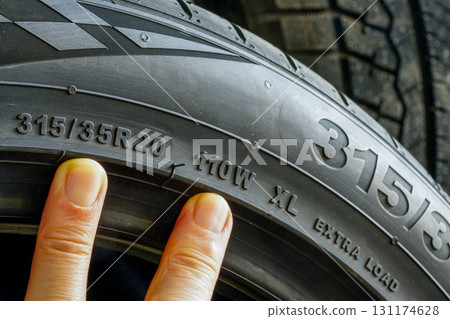 Close-up of car tire sidewall showing size 315-35R20 with 110W XL load and speed rating markings Close-up of car tire sidewall showing size 315-35R20 with 110W XL load and speed rating markings 131174628