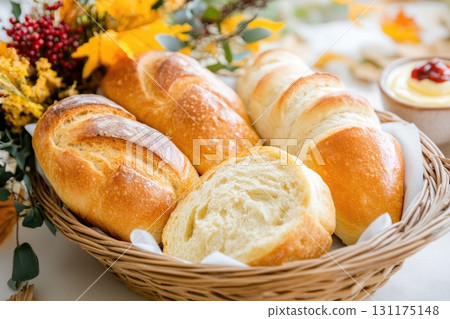 Rustic bread basket with autumn decor and butter cubes on white cloth 131175148