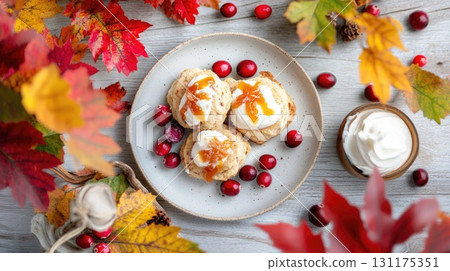Autumn cranberry scones with whipped cream and maple syrup on a rustic plate 131175351