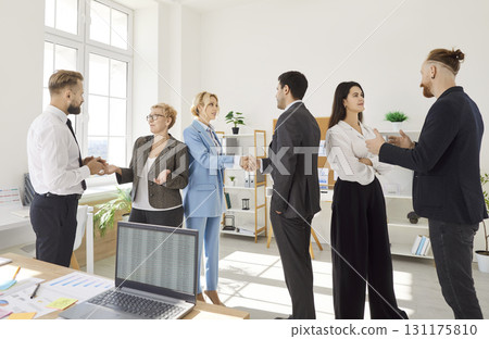 Group of business people in office exchanging handshakes, sharing ideas, collaborating on meeting. 131175810