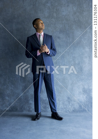 Man in suit standing against wall 131176304