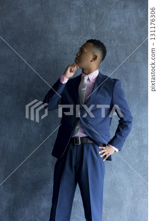 Man in suit standing against wall 131176306