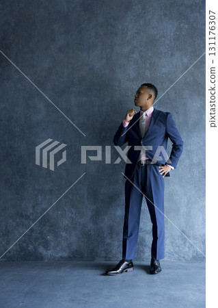Man in suit standing against wall 131176307
