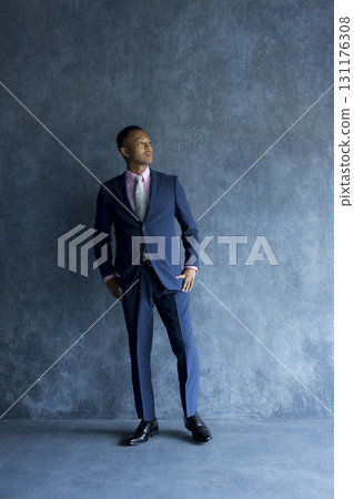 穿西裝的男人靠著牆站著 穿西裝的男人靠著牆站著 131176308