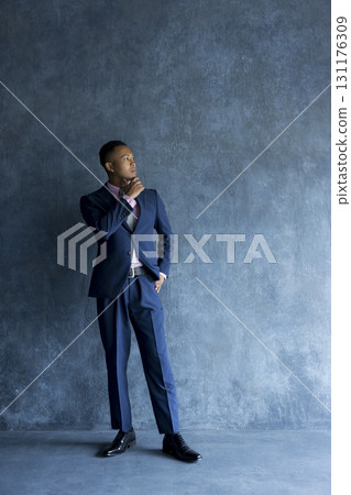Man in suit standing against wall 131176309