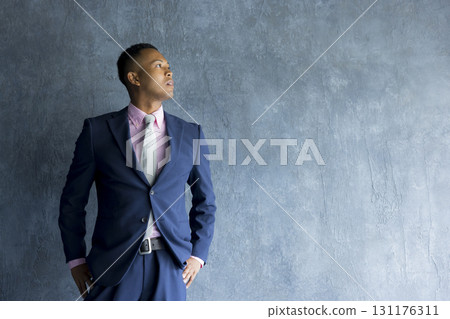 Man in suit standing against wall Man in suit standing against wall 131176311