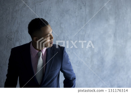 Man in suit standing against wall 131176314