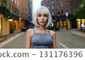 Half-length portrait of seductive slim platinum blonde caucasian young woman in tight grey top looking at camera outdoors in empty street of modern city at dusk. Digital art illustration. 131176396