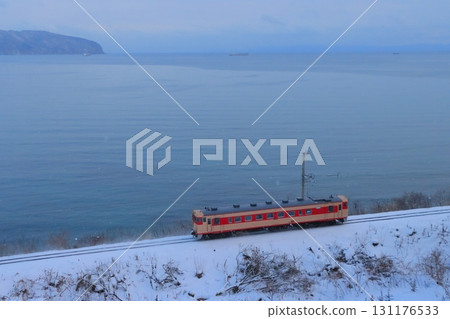 Dounan Isaribi Railway Kiha 40 series diesel railcar (JNR express color) running with the freezing cold Hakodate Bay in the background_Photo taken on 2020/12/27 131176533