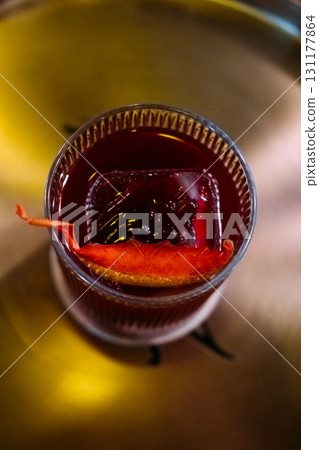 Citrus cocktail. Refreshing liquor. Bright aromatic negroni in glass. Alcoholic red drink ice cube orange fruit slice on metal tray. 131177864