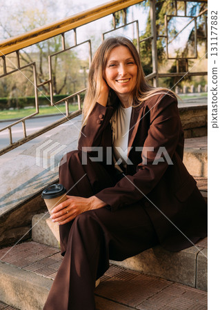 Urban lifestyle. Business break. Cheerful happy relaxed woman enjoying pleasant day with hot tea in paper cup. Urban lifestyle. Business break. Cheerful happy relaxed woman enjoying pleasant day with hot tea in paper cup. 131177882