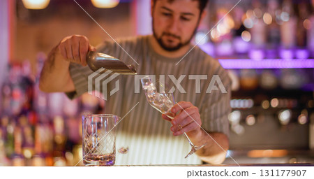 Preparing cold drink. Barkeeper workspace. Man pouring ice cubes with scoop in wineglass. Professional worker making refreshing beverage. 131177907