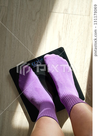 Woman feet on digital weight scale with kilogram display. Woman feet on digital weight scale with kilogram display. 131178069