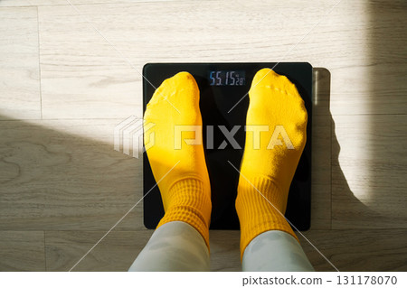 Woman standing on digital weight scale in yellow socks. Personal weight control and health monitoring concept. 131178070