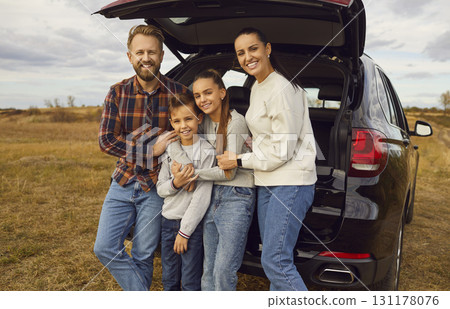 Happy smiling family with children looking at camera sitting on the trunk of car enjoying weekend. 131178076