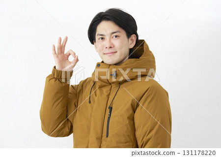 Man wearing down jacket OK sign white background 131178220