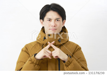 A man wearing a down jacket makes a gesture of the cross on a white background 131178230