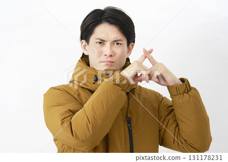 A man wearing a down jacket makes a gesture of the cross on a white background 131178231