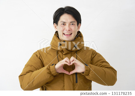 穿著羽絨外套的男人在白色背景上做出心形手勢 131178235