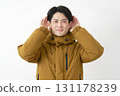 A man wearing a down jacket listening carefully on a white background 131178239