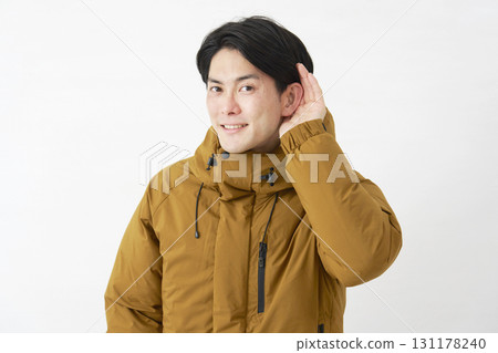 A man wearing a down jacket listening carefully on a white background A man wearing a down jacket listening carefully on a white background 131178240