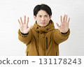 A man wearing a down jacket, posing in a restraining manner, white background 131178243