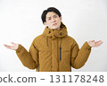 A man wearing a down jacket is astonished, looking at the camera on a white background 131178248