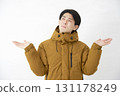 A man wearing a down jacket is astonished on a white background 131178249
