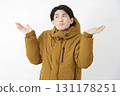 A man wearing a down jacket is astonished on a white background 131178251