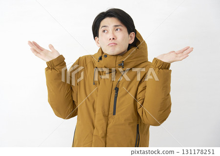 A man wearing a down jacket is astonished on a white background A man wearing a down jacket is astonished on a white background 131178251