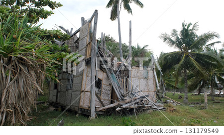Stormy winds shake palm trees with bamboo hut debris scattered after powerful coastal typhoon Stormy winds shake palm trees with bamboo hut debris scattered after powerful coastal typhoon 131179549