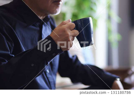 A senior man enjoying a drink from a mug at home. A senior man enjoying a drink from a mug at home. 131180786