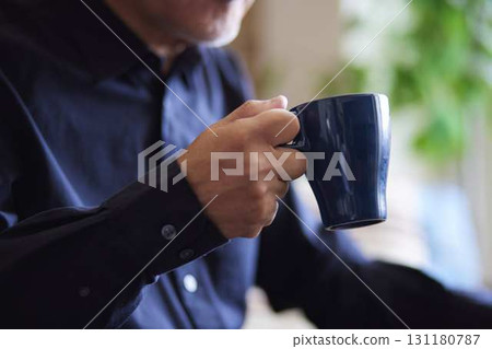 客廳裡,一位老人的手拿著一個杯子。 客廳裡,一位老人的手拿著一個杯子。 131180787