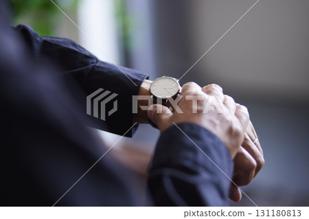 The hands of a senior Japanese man checking the time on his wristwatch 131180813