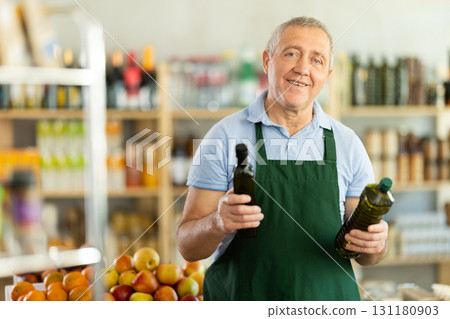 Elderly man seller offers olive oil in grocery store 131180903