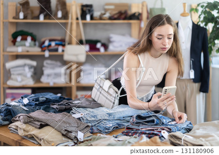 Selective young woman scanning QR-code on pantaloons in clothing store Selective young woman scanning QR-code on pantaloons in clothing store 131180906