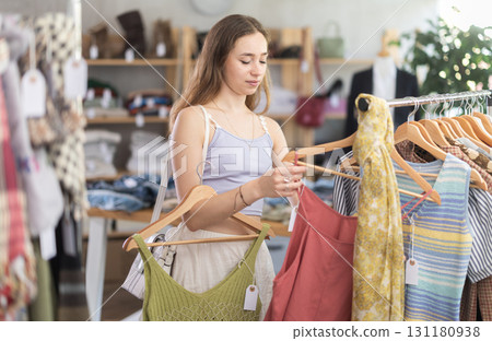 Positive young woman choosing something for summer in clothing store 131180938