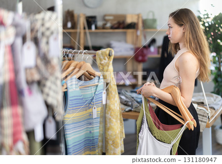 Selective young woman choosing something for summer in clothing store 131180947