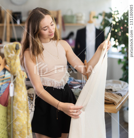 Selective young woman choosing something for summer in clothing store 131180985