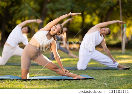 Girl participating in outdoor group yoga session in summer park Girl participating in outdoor group yoga session in summer park 131181121