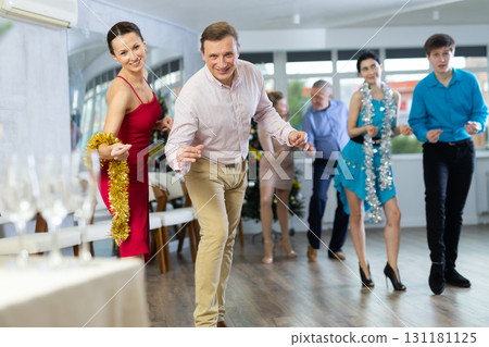 Cheerful adult couple dancing rock-n-roll during holiday eve office gathering 131181125