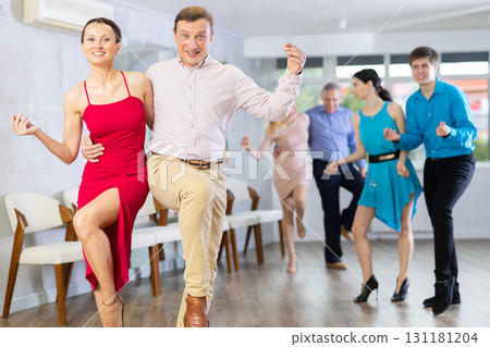 Cheerful adult couple practicing vigorous lindy hop in dance class 131181204