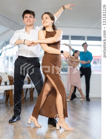 Hispanic guy enjoying merengue with female partner in dance class Hispanic guy enjoying merengue with female partner in dance class 131181226