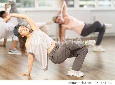 Girl and her students perform hip hop dance on one bent leg, movement in horizontal plane near floor Girl and her students perform hip hop dance on one bent leg, movement in horizontal plane near floor 131181299